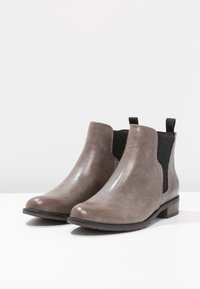 Bottines en simili cuir gris avec panneaux latéraux élastiques, bout rond et petit talon. Texture lisse et design minimaliste.