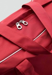 Sac en nylon rouge avec une fermeture éclair sur le dessus, présentant des tirettes en métal argenté et des coutures d'accent blanches sur une surface lisse.