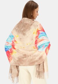 Lekki beżowy szalik z kolorowymi kwiatowymi wzorami w czerwonym, niebieskim i żółtym. Miękka faktura z frędzlami, idealny do warstwowego noszenia.