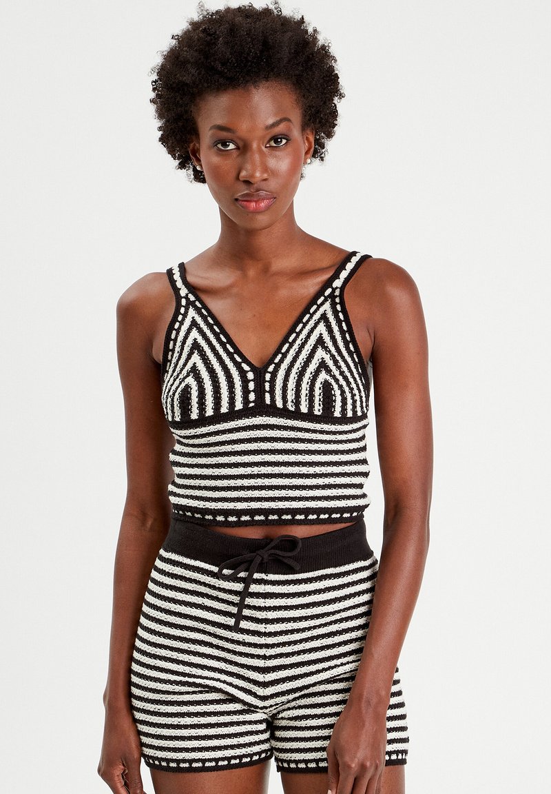 Zwart-witte gestreepte gebreide tanktop met V-hals, bijpassende shorts met elastische tailleband en trekkoord. Geweven patroon overal.