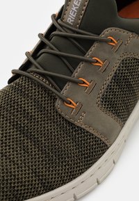 Scarpa da uomo in mesh e pelle verde oliva scuro. Presenta dettagli arancioni, punta arrotondata e suola bianca flessibile con motivo testurizzato.