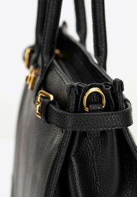 Borsa a mano in pelle nera con superficie testurizzata, dettagli in metallo dorato e due manici robusti. Chiusura con zip dettagliata nella parte superiore.