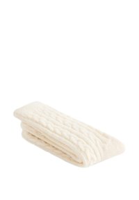 Zložena kremasta pletena odeja z reliefnim vzorcem kaveljčkov, narejena iz mehke, puhaste tkanine. Vidni so poudarjeni robovi.