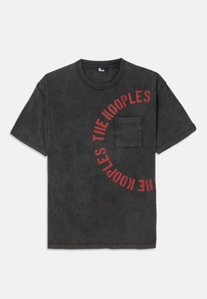 Zwarte katoenen T-shirt met een ronde graphic in rode tekst met de tekst "THE KOOPLES", voorzien van een zak aan de voorkant en een ontspannen pasvorm.