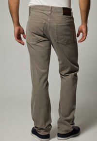 Jasnoszare spodnie z sztruksu o prostym kroju, z dwoma tylnymi kieszeniami i brązową skórzaną naszywką na pasku.