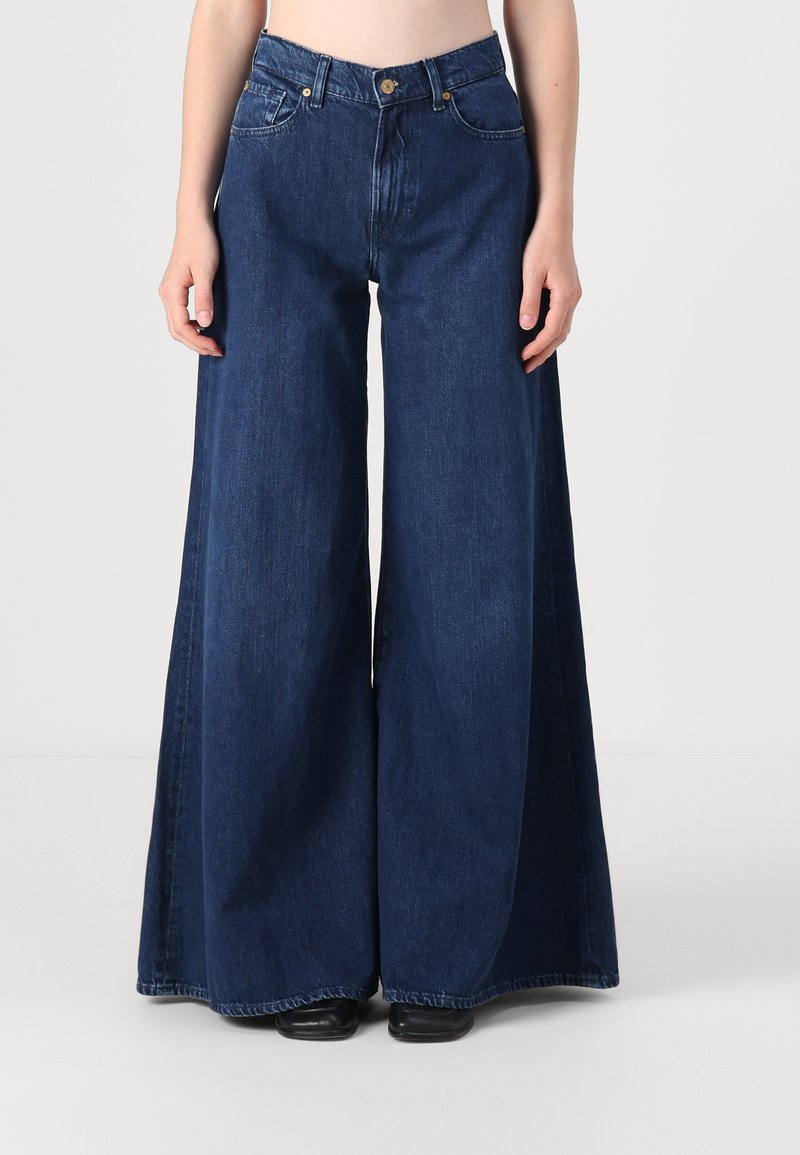 Korkeat vyötäröiset, tummansiniset, väljät farkut, joissa on suuret takataskut ja hieno haalistuma. Klassinen viiden taskun muotoilu hopeaosilla.