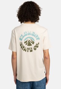 Krémové tričko s grafickým designem hor a textem "ELEMENT SKATE CO." v modré a zelené barvě, krátké rukávy, uvolněný střih.