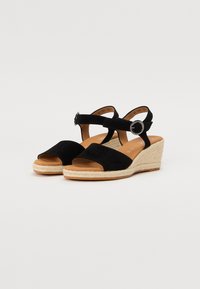 Sandales à talons compensés en suédine noire avec une semelle de style espadrille, présentant deux bandoulières et un détail de boucle ronde sur la bride de la cheville.