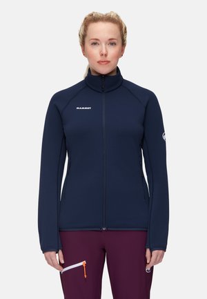 Navy blue zip-up jacket with high collar, made from soft fabric, featuring a logo on the chest and zippered pockets on the sides.