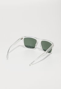 Ochelari de soare cu ramă transparentă, lentile verzi, lentile pătrate și brațe subțiri. Design curat, fără modele sau accente vizibile.