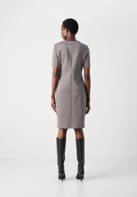 Robe ajustée jusqu'aux genoux en tissu à motifs avec des manches courtes, dotée d'un col rond et d'une texture lisse, associée à des bottes noires haute jusqu'aux genoux.