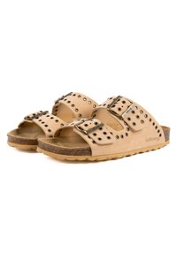 Sandales beige clair avec deux larges sangles, quincaillerie en métal et découpes rondes, une semelle en liège et une semelle extérieure texturée pour une meilleure adhérence.