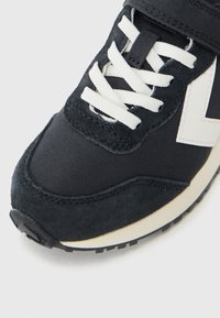 Donkerblauwe sneaker met een combinatie van suede en textiele materialen, witte veters, een opvallend off-white logo en een gestructureerde rubberen zool.