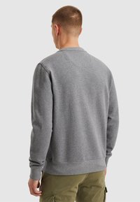 Sudadera gris con cuello redondo y puños acanalados. Fabricada con una tela suave. La vista trasera muestra una textura suave y sutiles detalles de costura.