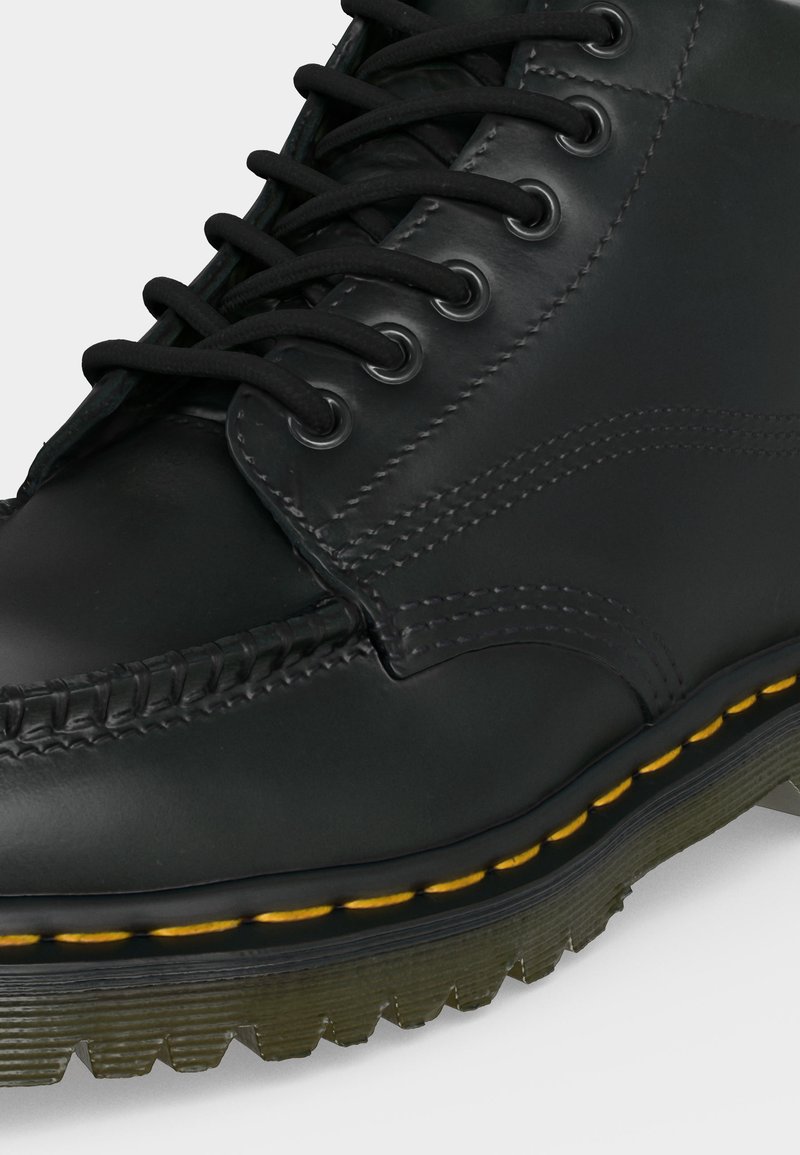 Schwarzer Leder-Schnürstiefel mit gelber Naht und dicker, gerillter Gummisohle.