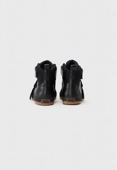  svarte høyhælte joggesko med en glatt læroverflate, meshpaneler og gummisåle, med en borrelåsrem og logo på hælen.