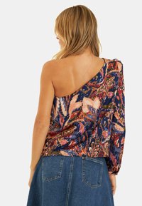Asymmetrisch bovenstuk met één lange mouw, heeft een multikleurig bloemenpatroon in roze, blauw en crème op een donkere achtergrond.