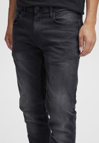 Zwarte denim jeans met een slim fit, voorzien van vijf zakken, een knoopsluiting en een lichte vervaging aan de voorkant voor textuurcontrast.