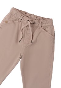 Pantaloni cargo beige con vita elastica, chiusura con cordoncino e tasche frontali. Il tessuto è liscio con cuciture minimamente visibili.