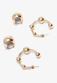 Pendientes de metal dorado con un diseño de aro redondo y acabados suaves. Un par tiene un acento esférico, el otro tiene un patrón de bolas enlazadas.