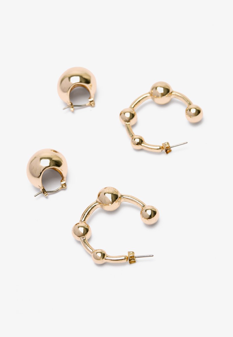 Boucles d'oreilles en métal doré avec un design de boucle ronde aux finitions lisses. Une paire présente un accent sphérique, l'autre un motif de boules liées.