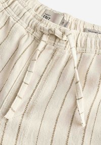 Lys beige afslappede shorts med gyldne vandrette striber, elastisk talje og justerbar snor for en sikker pasform.