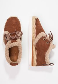 Brown suede shoes with beige fleece lining, round toe, braided laces, and jute accents along the sole. Flat white rubber outsole.