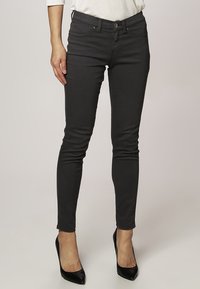 Svarta skinny jeans med en slät yta, med framfickor, knappstängning och en figurnära design som avsmalnar vid vristen.