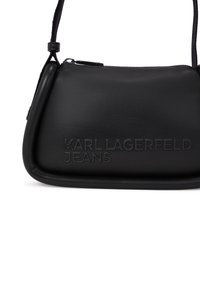 Juoda odinė Rankinė su išlenktu pavidalu, su iškiliu "KARL LAGERFELD JEANS" logotipu, užtrauktuko uždarymu ir reguliuojama juosta. Lygi tekstūra.