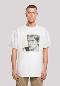 Hvid oversized t-shirt med et sort og gråt portrætprint på forsiden, med korte ærmer og rund halsudskæring.