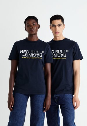 T-shirt in cotone blu navy con "RED BULL RACING" e dettagli del marchio in testo bianco e giallo, abbinato a jeans in denim blu.