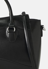 Black handbag made of textured synthetic material. Features double handles, detachable shoulder strap, and silver-tone hardware accents.