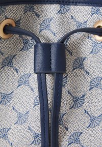 Tessuto blu con motivo su uno sfondo cremoso e testurizzato, con dettagli in pelle blu navy e un occhiello con due spallacci regolabili.