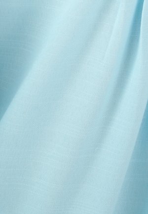 Lichtblauwe stof met zichtbare weefstructuur en zachte plooien die subtiele schaduwen creëren.