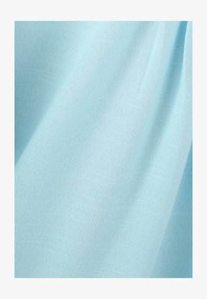 Lichtblauwe stof met zichtbare weefstructuur en zachte plooien die subtiele schaduwen creëren.