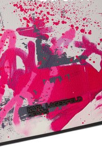 Material alb texturat cu pete abstracte vibrante roz și gri; prezintă logo-ul „KARL LAGERFELD JEANS” în negru.