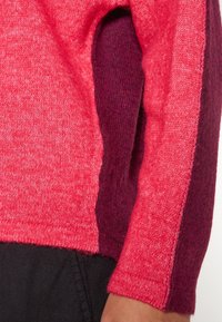 Rosa und burgunderfarbenes Sweatshirt mit strukturiertem Strick. Verfügt über ein auffälliges Farbblockdesign an den Ärmeln, mit einer standardmäßigen Passform und gerippten Bündchen.