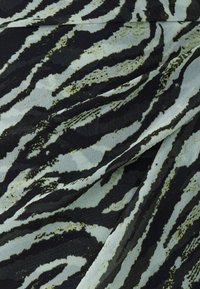 Stof met een zwart en lichtgroen zebra-streep patroon, met een zachte textuur en subtiele glans, gevouwen om diepte en vloeiendheid te tonen.