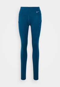 Leggings atletici teal con una vita alta, dotati di tasche laterali e cuciture a contrasto. Logo posizionato nella parte superiore sinistra anteriore.