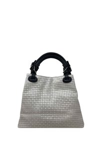Torebka z plecionego skóry w kolorze srebrnym z teksturowanym wzorem w kratkę. Czarne skórzane uchwyty z srebrnymi akcentami.