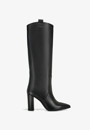 Botte noire en cuir, haute avec un bout pointu, un talon bloc haut et une languette de tirage en haut de la tige.