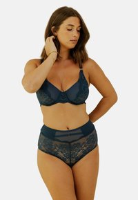 Soutien-gorge en dentelle bleu marine avec armatures et bretelles réglables, associé à une culotte taille haute en dentelle et en maille, arborant des motifs floraux et une touche élégante.