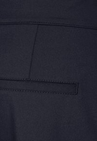 Marinblått tyg med en slät texture, som har en liten weltficka och plana sömmar för en ren design. Lämplig för avslappnad klädsel.