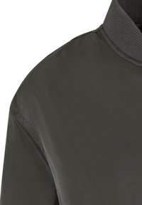 Dunkelgrüne Bomberjacke aus einem glatten, leichten Stoff. Sie verfügt über einen gerippten Kragen und dezente Nahtdetails an den Schultern.