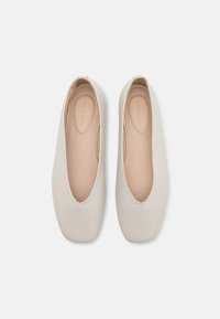 Beige ballettskor med en jevn skinnutside, rund tå og myk innersåle. Har et lavprofildesign med minimale detaljer.