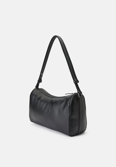 Borsa a spalla in pelle nera con una singola tracolla regolabile e chiusura con cerniera, esposta su uno sfondo chiaro e semplice.