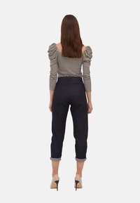 Dámské tričko s balónovými rukávy v černobílém pruhu, v kombinaci s tmavými džíny s krátkou nohavicí, na které jsou ohrnuté manžety, a béžovými lodičkami.