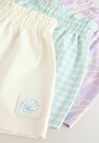 Drei Shorts: eine in Creme, eine in hellblau kariert und eine in Lavendel mit gelbem Muster. Mit elastischem Bund und Logopatch.
