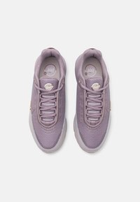 Baskets de course lilas avec une tige en mesh, surface texturée et forme allongée. Caractéristiques : un bout arrondi, des lacets et des couleurs d'accent.