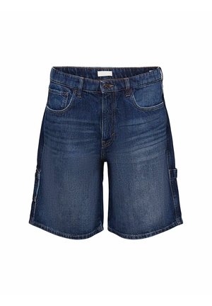 Szorty jeansowe w ciemnym niebieskim kolorze, o luźnym kroju, z bocznymi kieszeniami i brzegiem z lekkim postrzępieniem. Połączone z zielonym, graficznym t-shirtem i białymi trampkami.